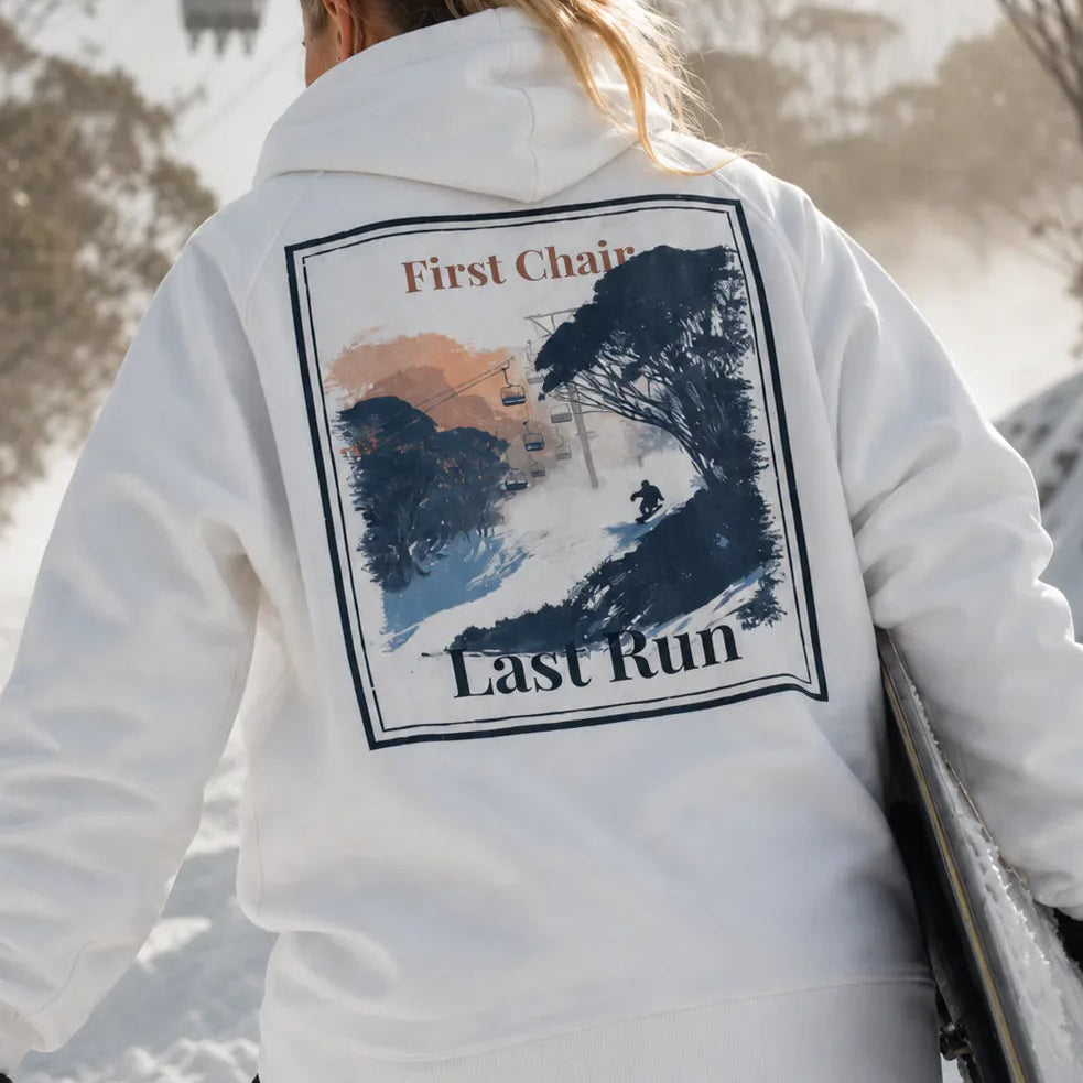 White hoodie with back graphic print; text reads "First Chair" and "Last Run"