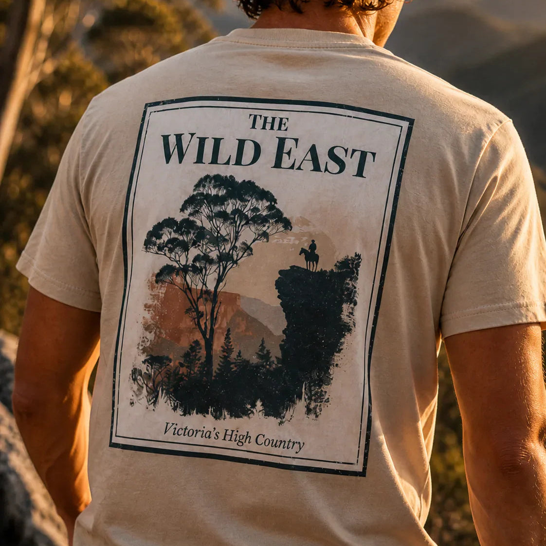 T-shirt organica con stampa grande sul retro: paesaggio e testo The Wild East